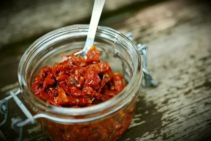 Einweckgläser mit Vorräten und Tomaten in einem Vorratsregal