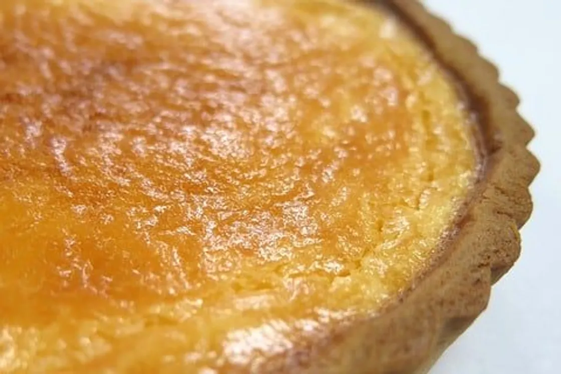 Stück Zitronen-Buttermilch-Tarte mit Puderzucker und Zitronenzeste